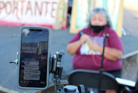 An advocate for racial equality is livestreamed in Phoenix during the "Peaceful, Prayerful Protest" June 13. The Spanish banner in the cellphone reads "Black Lives Matter."