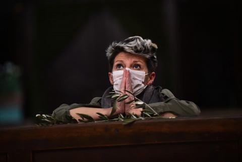 A woman wearing a protective mask due to the coronavirus pandemic prays inside the Church of the Sacred Heart of Jesus on Palm Sunday, April 5 in Turin, Italy.